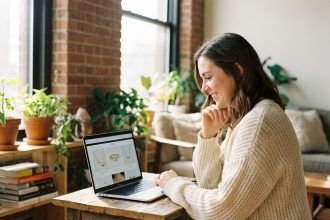 Jeune femme souriante utilisant un ordinateur portable dans un intérieur cosy